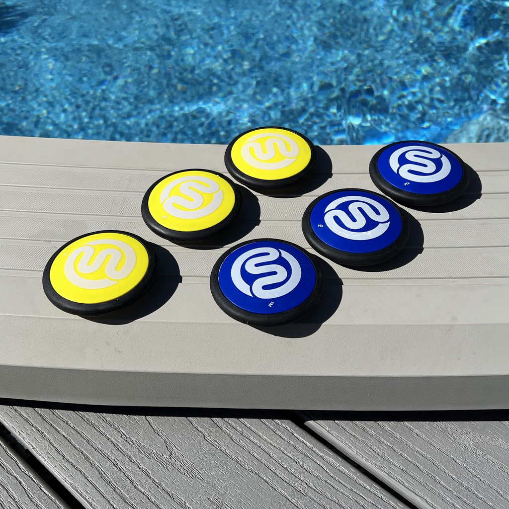 6 original Squire above-ground pool game discs on top rail or ledge of swimming pool